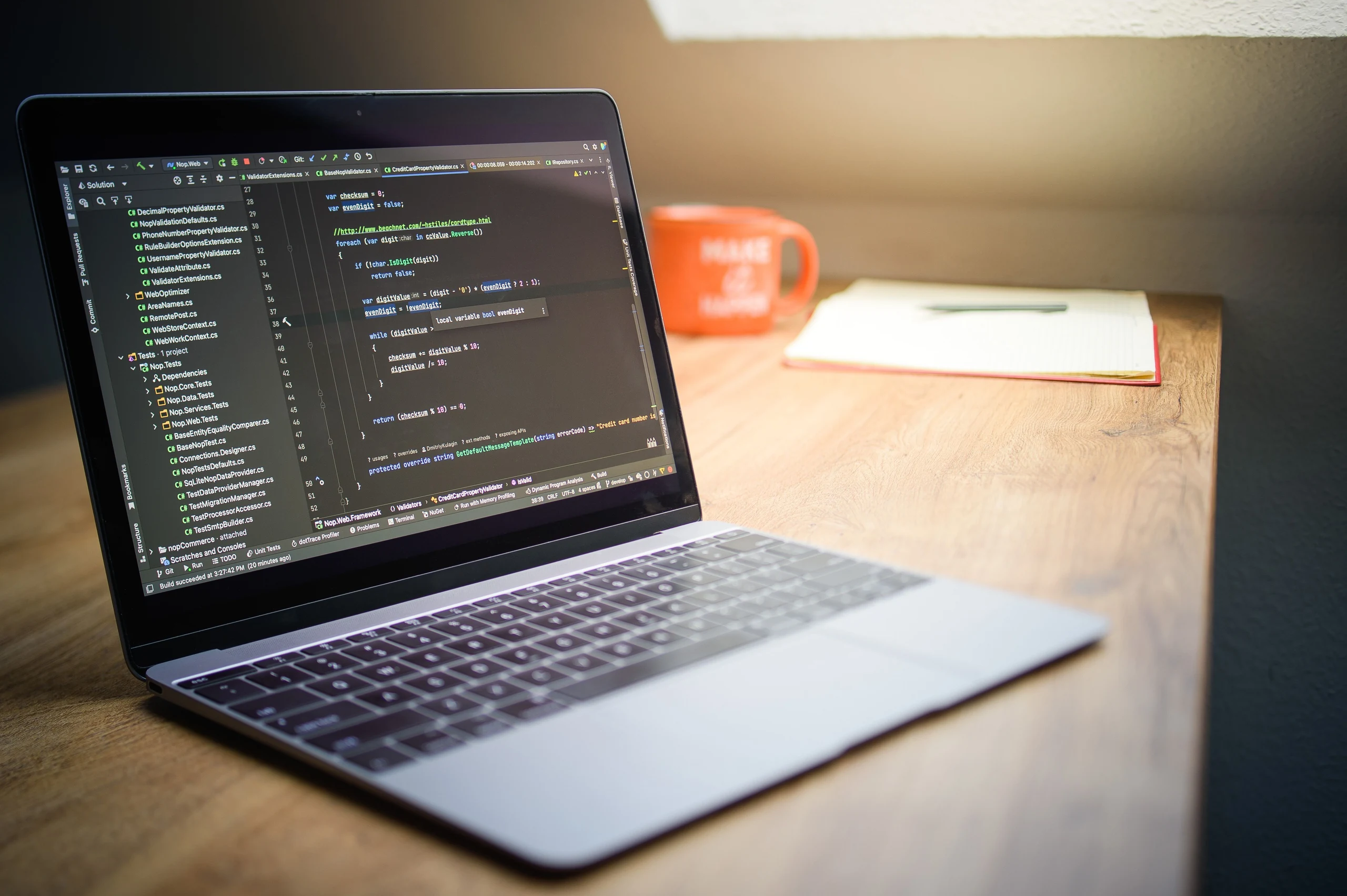 Un ordinateur portable affichant du code, à côté d’un carnet sur un bureau.
